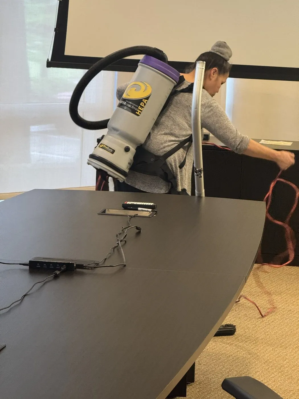 Crew member using a backpack vacuum on office carpet in Dallas-Fort Worth