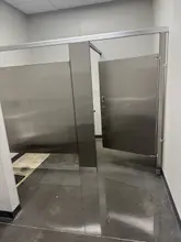 Commercial restroom with stainless partitions and a freshly cleaned floor in Dallas-Fort Worth