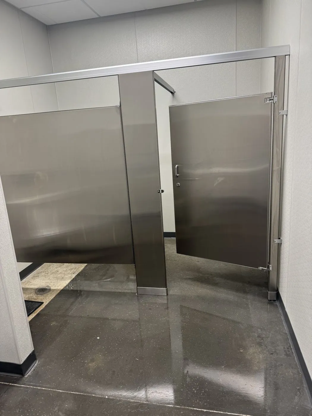 Commercial restroom with stainless partitions and a freshly cleaned floor in Dallas-Fort Worth