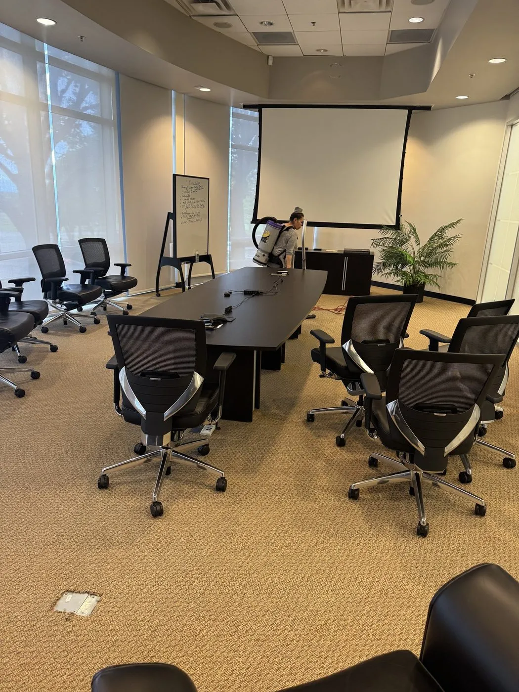 Daltex crew member vacuuming a Dallas-Fort Worth conference room with a backpack vacuum
