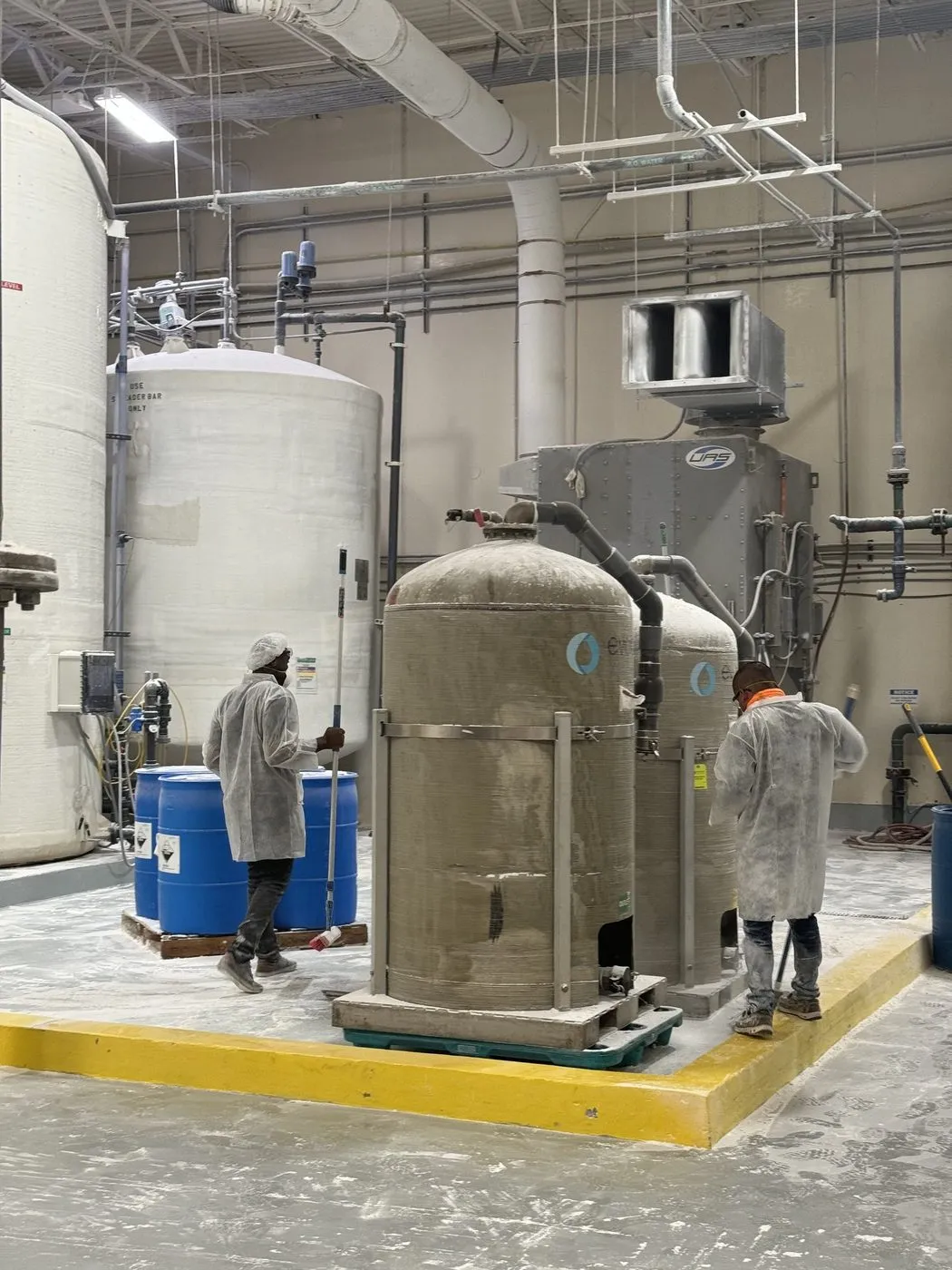 Daltex crew in protective suits cleaning around industrial tanks in Dallas-Fort Worth