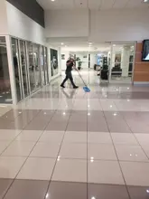 Daltex crew member mopping a polished tile corridor in a Dallas-Fort Worth commercial building