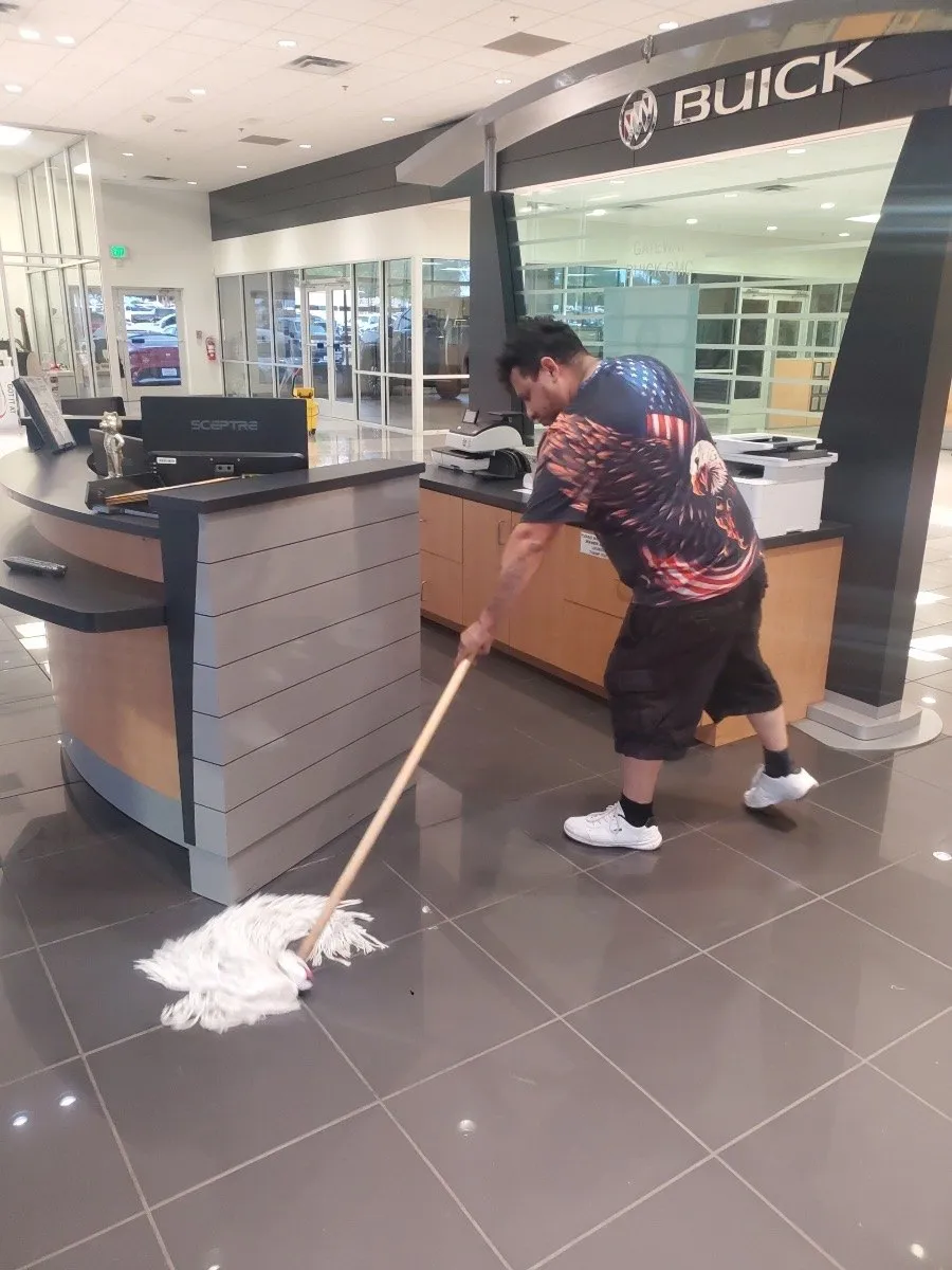 Daltex crew member mopping a dealership showroom floor in Dallas-Fort Worth