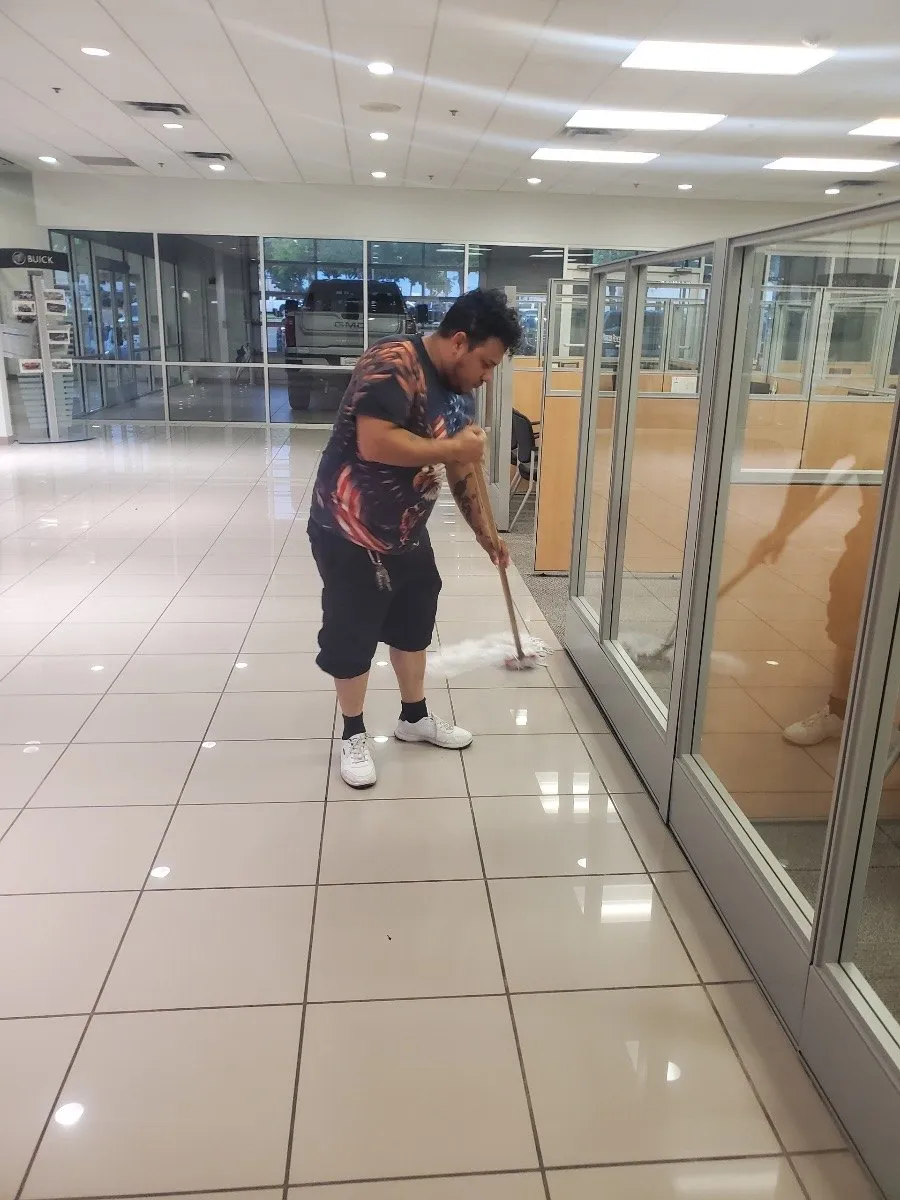 Crew member mopping tile beside glass-walled offices in a Dallas-Fort Worth building