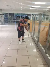 Crew member mopping tile beside glass-walled offices in a Dallas-Fort Worth building
