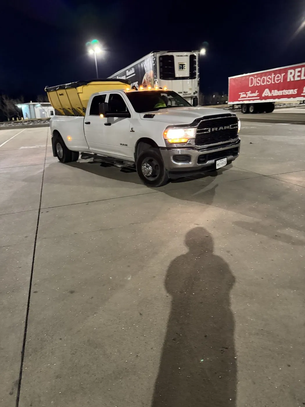 Spreader truck working a Dallas-Fort Worth commercial lot at night during winter weather